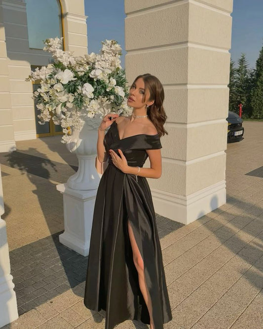 Robe de soirée noire longue, élégante et fendue, coupe trapèze, épaules dénudées, style classique, idéale pour les bals de fin d'année et les dîners. Modèle AB2097.