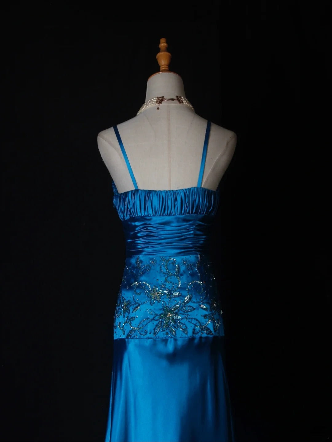 Robe de bal longue vintage en satin bleu à fines bretelles et sequins, coupe trapèze, ornée de perles et d'un corsage perlé. Idéale pour un 18e anniversaire. Référence AS282.