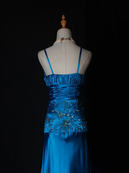 Robe de bal longue vintage en satin bleu à fines bretelles et sequins, coupe trapèze, ornée de perles et d'un corsage perlé. Idéale pour un 18e anniversaire. Référence AS282.