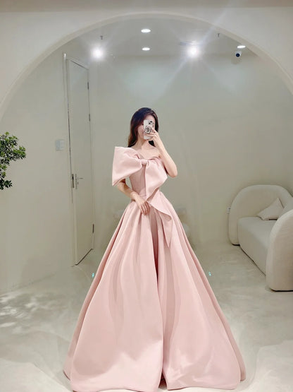 Robe de bal longue rose satinée, bustier, coupe trapèze, ornée d'un nœud papillon. Idéale pour un 18e anniversaire. Modèle N301.